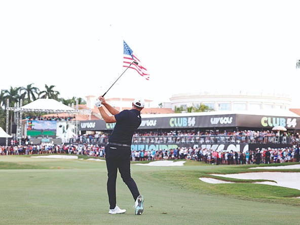 a golfer taking a swing of his club infront of an american flag